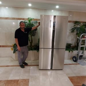 אדם עומד ליד מקרר נירוסטה גדול