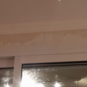 קיר צבוע חלקית מעל חלון עם סימני צבע