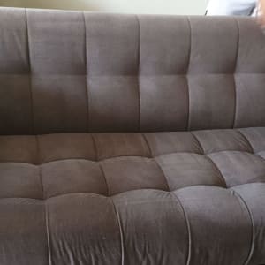 ספה אפורה עם יד מחזיקה מברשת ניקוי