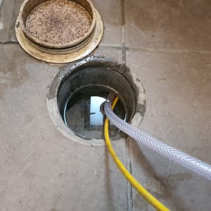 צינורות צהובים ואפורים בתוך פתח ביוב על רצפה