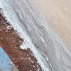 קיר אטום בחומר לבן ליד אדמה רטובה