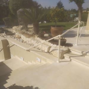 מעקה לבן על מדרגות חיצוניות עם צמחייה מסביב