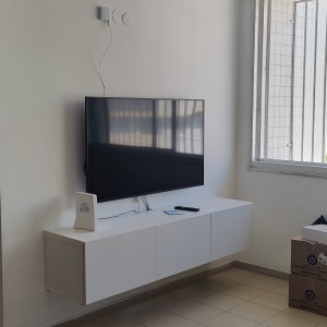 חלון עם תריסים פתוחים למחצה ליד טלוויזיה תלויה