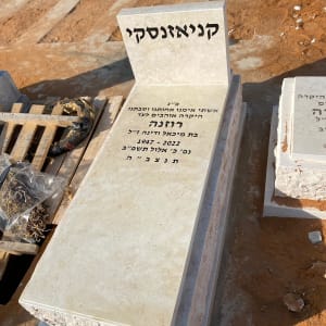 מצבה עם כיתוב בעברית על רקע אדמה