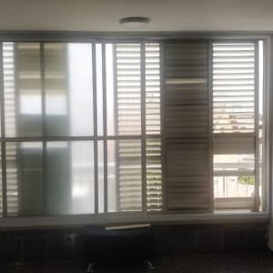 חלון עם תריסים פתוחים וחלקים מונחים על הרצפה