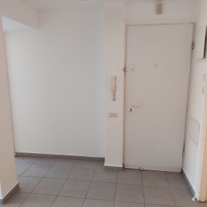 קיר לבן עם דלת לבנה ורצפת אריחים אפורה