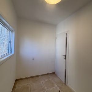 חדר קטן עם רצפת אריחים ודלת לבנה