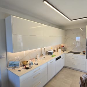 מטבח מודרני עם ארונות לבנים ומשטח עבודה נקי