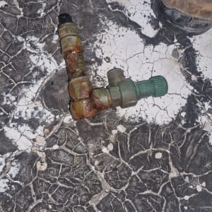 ברז מתכת חלוד על רצפה סדוקה