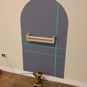 מדף עץ מותקן על קיר עם כלי עבודה על הרצפה