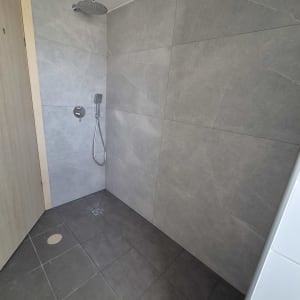 חדר אמבטיה עם אריחים אפורים ומקלחת
