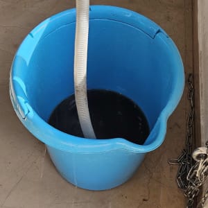 צינור ניקוז מזגן בתוך דלי כחול מלא מים