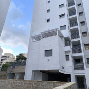 בניין גבוה עם מרפסת וגדר אבן