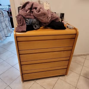 שידה עם בגדים מונחים עליה בחדר פנימי