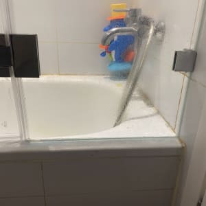 דלת זכוכית למקלחת עם ברז ומוצרים לניקוי