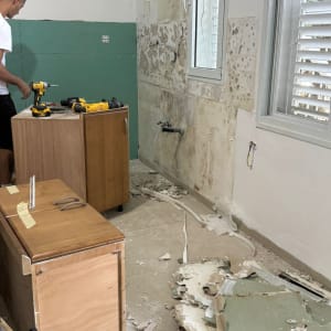 אדם עובד עם מקדחה בחדר בשיפוצים