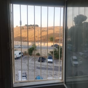 חלון פתוח עם סורגים מתכתיים נראים מבחוץ