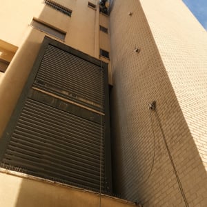 אדם עובד בגובה על בניין עם חבלים וכלים