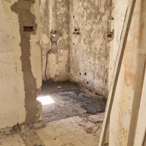 חדר בשיפוץ עם קירות חשופים ורצפה שבורה