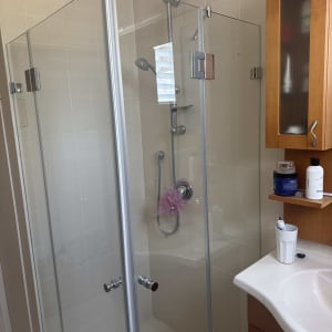 מקלחון זכוכית עם ראש מקלחת ורהיטים בחדר אמבטיה