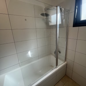 מקלחת עם דלת זכוכית ואמבטיה לבנה