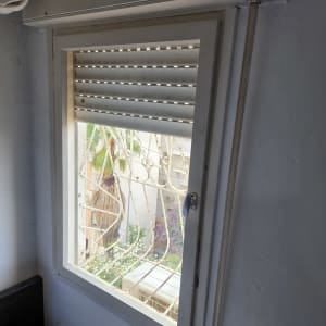 חלון זכוכית עם תריסים פתוחים ומסגרת לבנה