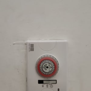 טיימר חשמלי על קיר עם חוגה ומתג הפעלה