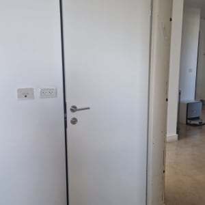 דלת לבנה עם ידית מתכת בחדר