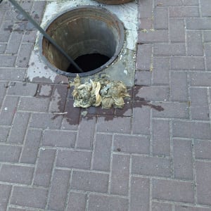 פתח ביוב עם פסולת על המדרכה