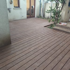 רצפת דק עץ בחצר עם צמחייה בצד