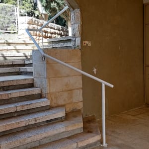 מעקה מתכת לבן ליד מדרגות אבן חיצוניות