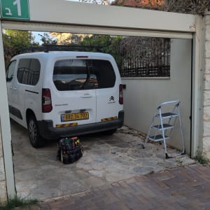 רכב עבודה של טכנאי תריסים לצד תיק כלים וסולם בחנייה