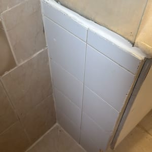 אריחי קרמיקה מותקנים בפינת חדר אמבטיה עם חיבורים חדשים