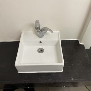 כיור לבן על משטח עץ כהה עם ברז כסוף