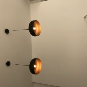 שני מנורות קיר עם נורות דולקות על קיר לבן