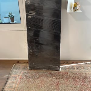 ארון שחור עטוף בניילון עומד על שטיח