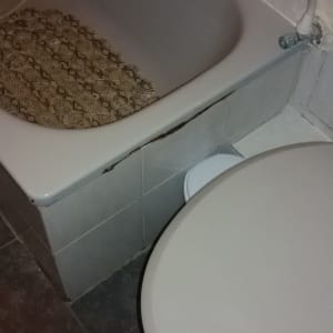 אמבטיה עם חיפוי פגום ליד אסלה