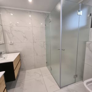 מקלחון זכוכית עם דלתות שקופות בחדר אמבטיה