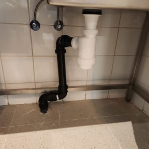 צנרת מתחת לכיור עם חיבורים וצינורות פלסטיק
