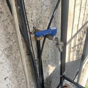 ברז מים כחול מותקן על קיר עם צינור מחובר