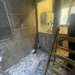 חדר בשיפוץ עם אריחים שבורים וסולם עץ