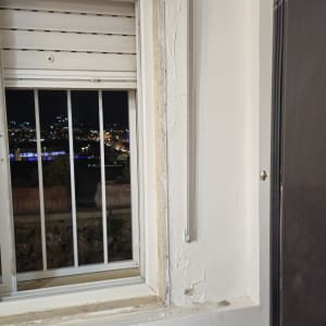 חלון עם תריסים ומסגרת מתכת בלילה