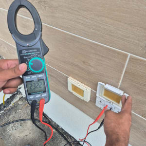 חשמלאי מודד מתח עם מד זרם ליד שקע חשמל