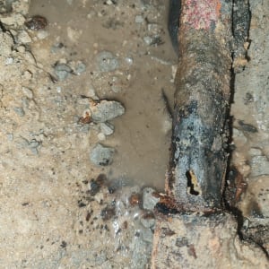 צינור חלוד עם חור ודליפת מים באדמה