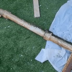 צינור חלוד על דשא מלאכותי עם כלי עבודה