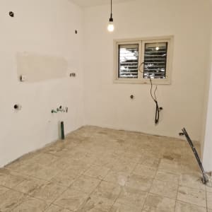 חדר ריק עם רצפת אריחים וקיר לבן