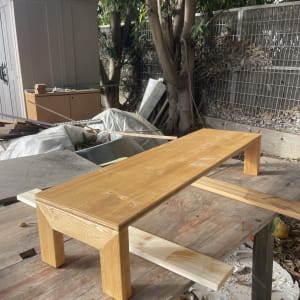 ספסל עץ על שולחן עבודה בחוץ ליד עצים וגדר