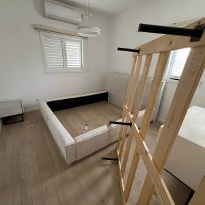 חדר עם מיטה מפורקת ורצפת עץ