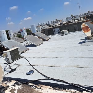 אדם עובד על איטום גג עם זפת ודליים