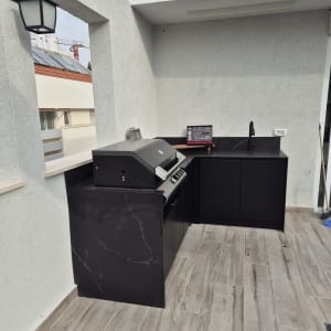 מטבח חוץ עם גריל, כיור ומחשב נייד על השיש